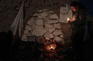 A relative lights a candle outside the main gate of a copper and gold mine where 33 miners are trapped underground at Copiapo