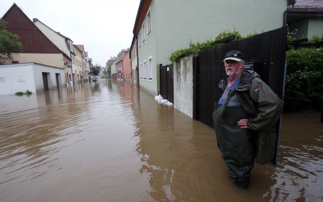 A resident stands at his property on a flooded street in the town of Grimma