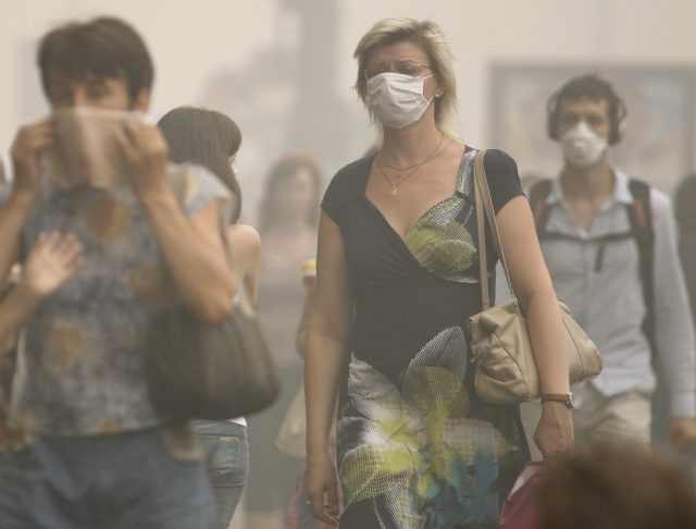 People, wearing masks and covering their faces with handkerchiefs to protect themselves from the smell of heavy smog, walk in Moscow