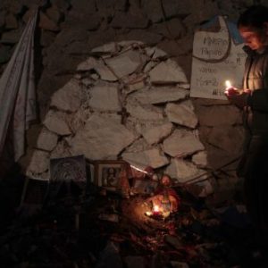 A relative lights a candle outside the main gate of a copper and gold mine where 33 miners are trapped underground at Copiapo